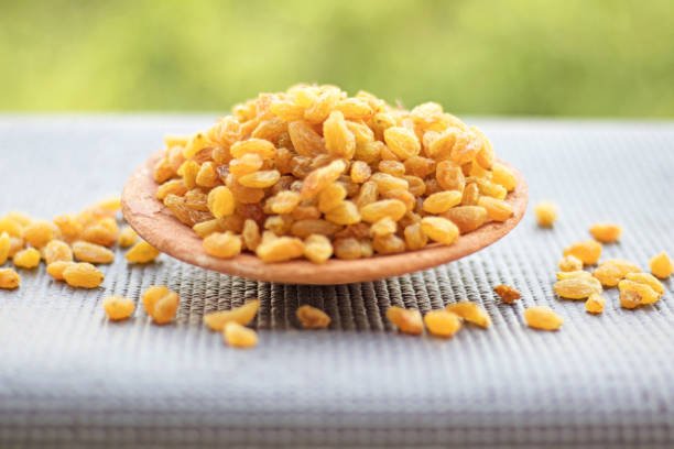 Heap of dry raisins in a bowl with natural background